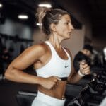 Młoda kobieta biegnie na bieżni w nowoczesnym klubie fitness