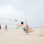 Siatkarze plażowi w wyskoku, walczą o piłkę na słonecznej plaży