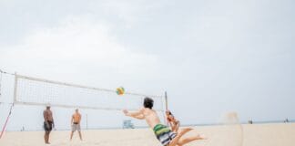 Siatkarze plażowi w wyskoku, walczą o piłkę na słonecznej plaży
