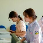 Trzy studentki AWF pracują przy komputerze w sali dydaktycznej