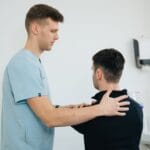 Fizjoterapeuta prowadzi terapię barku pacjenta w gabinecie
