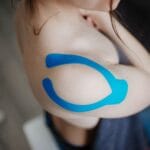 Zbliżenie barku z taśmami kinesiotaping po operacji w rehabilitacji